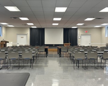 auditorium with tables and chairs set up in rows