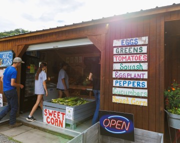 exterior of a farm store listing various vegetables for sale